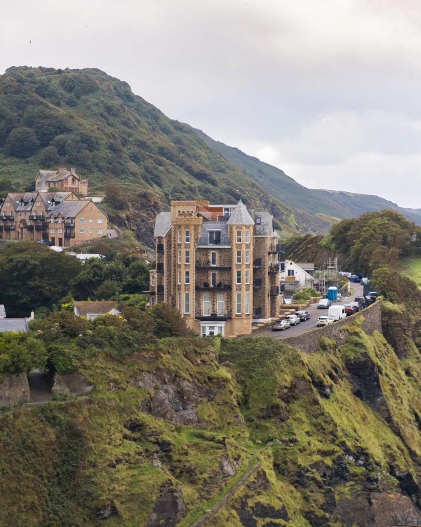 Historic building perched on a lush English cliffside with coastal views.