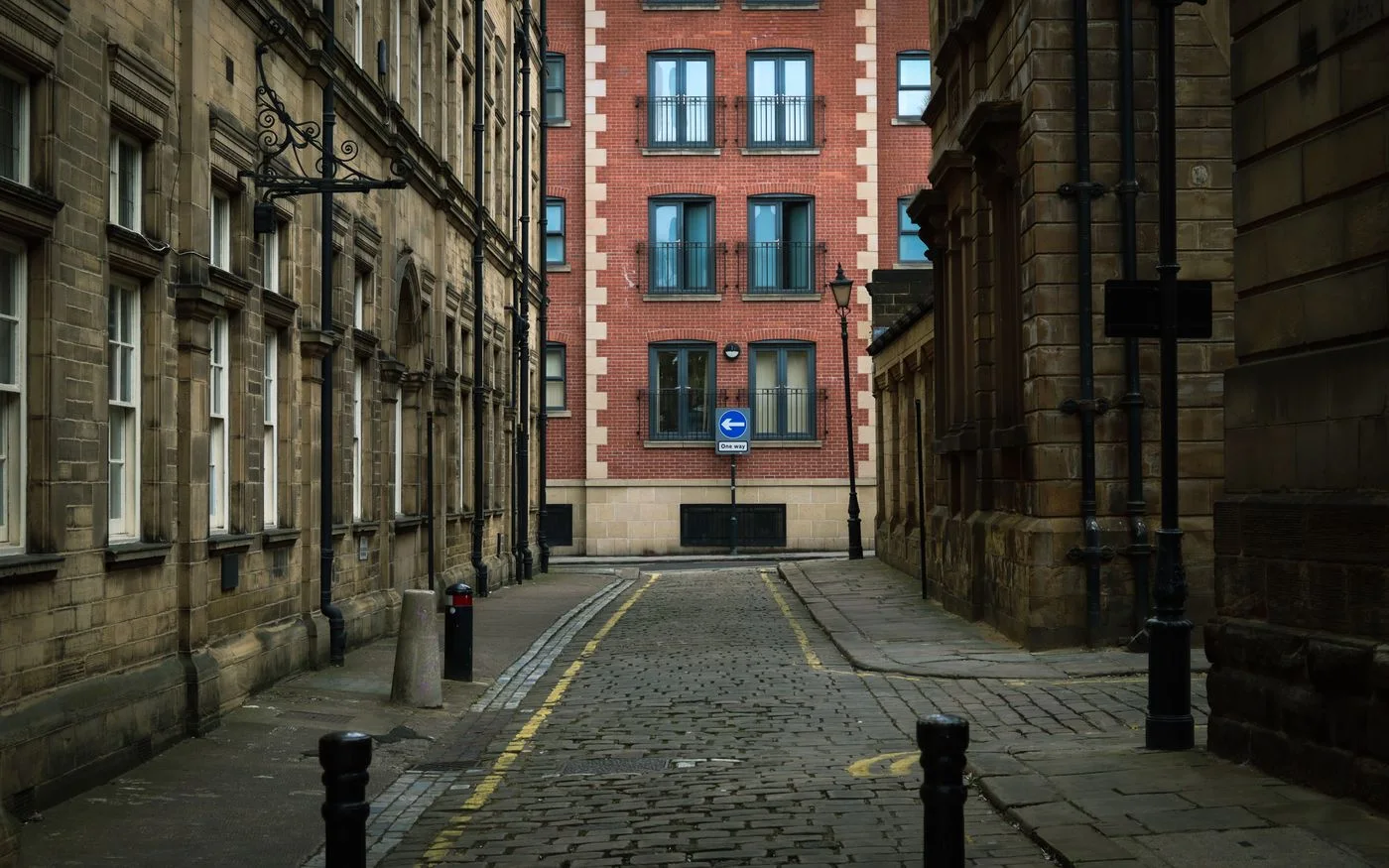 Narrow cobblestone street in Wakefield featuring classic brick and stone townhouses.