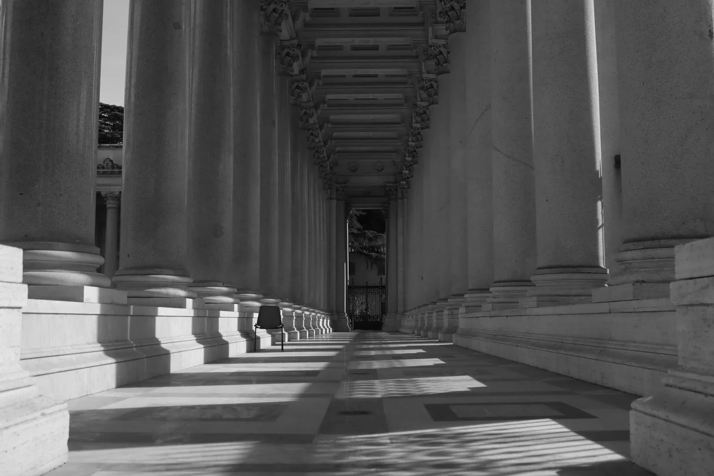 Black and white image of a classical columned corridor in Rome, Italy.