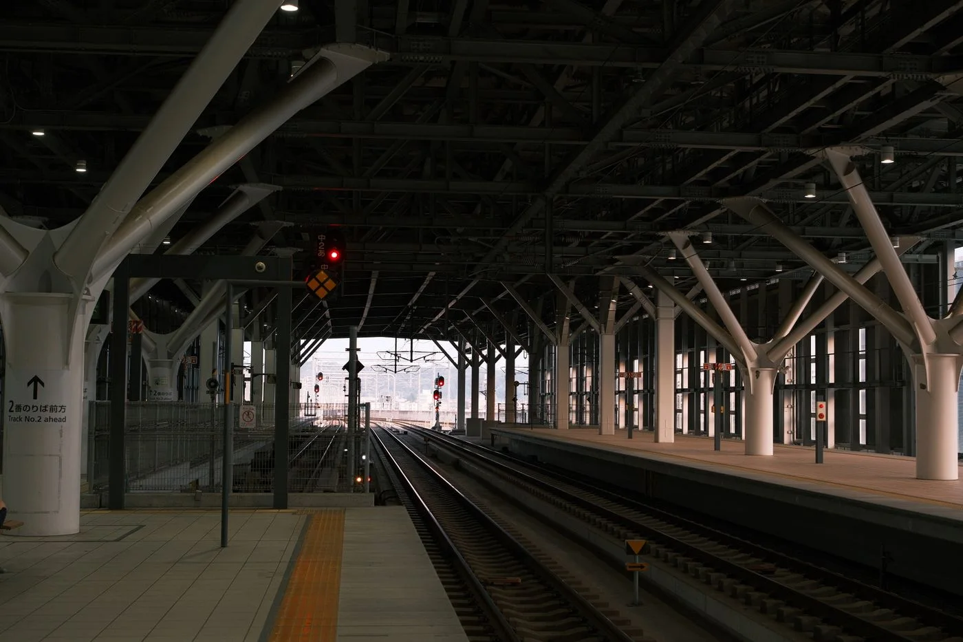 Empty railway platform in a modern Japanese train station, emphasizing architectural design.