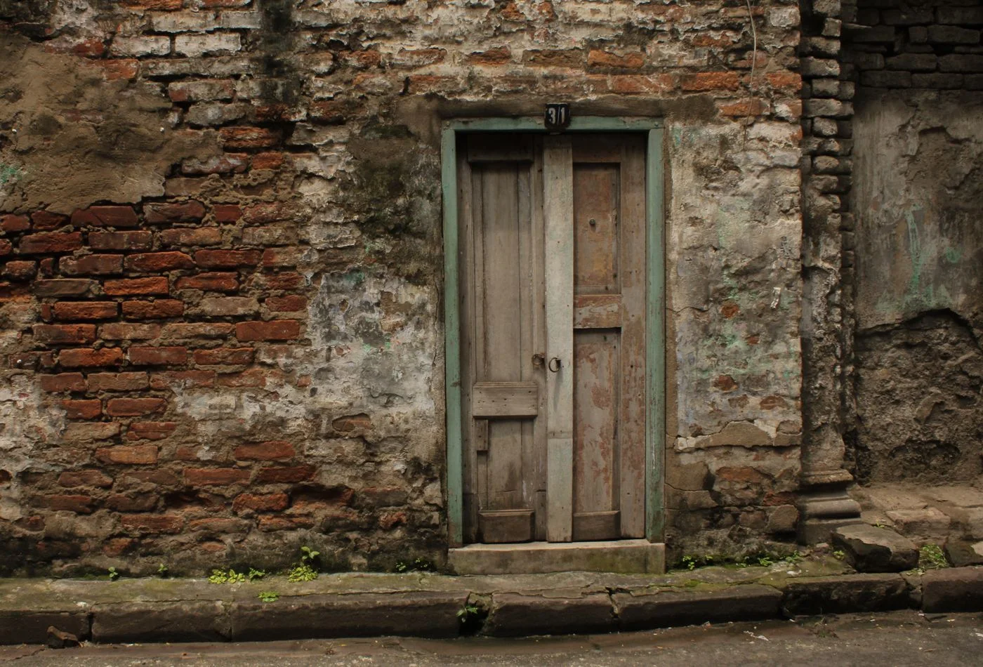 A vintage doorway set in a weathered brick wall in Kolkata, India, exuding old-world charm.
