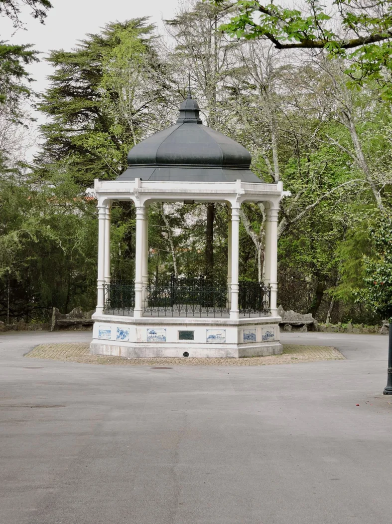 Charming white gazebo surrounded by lush greenery in a peaceful urban park.