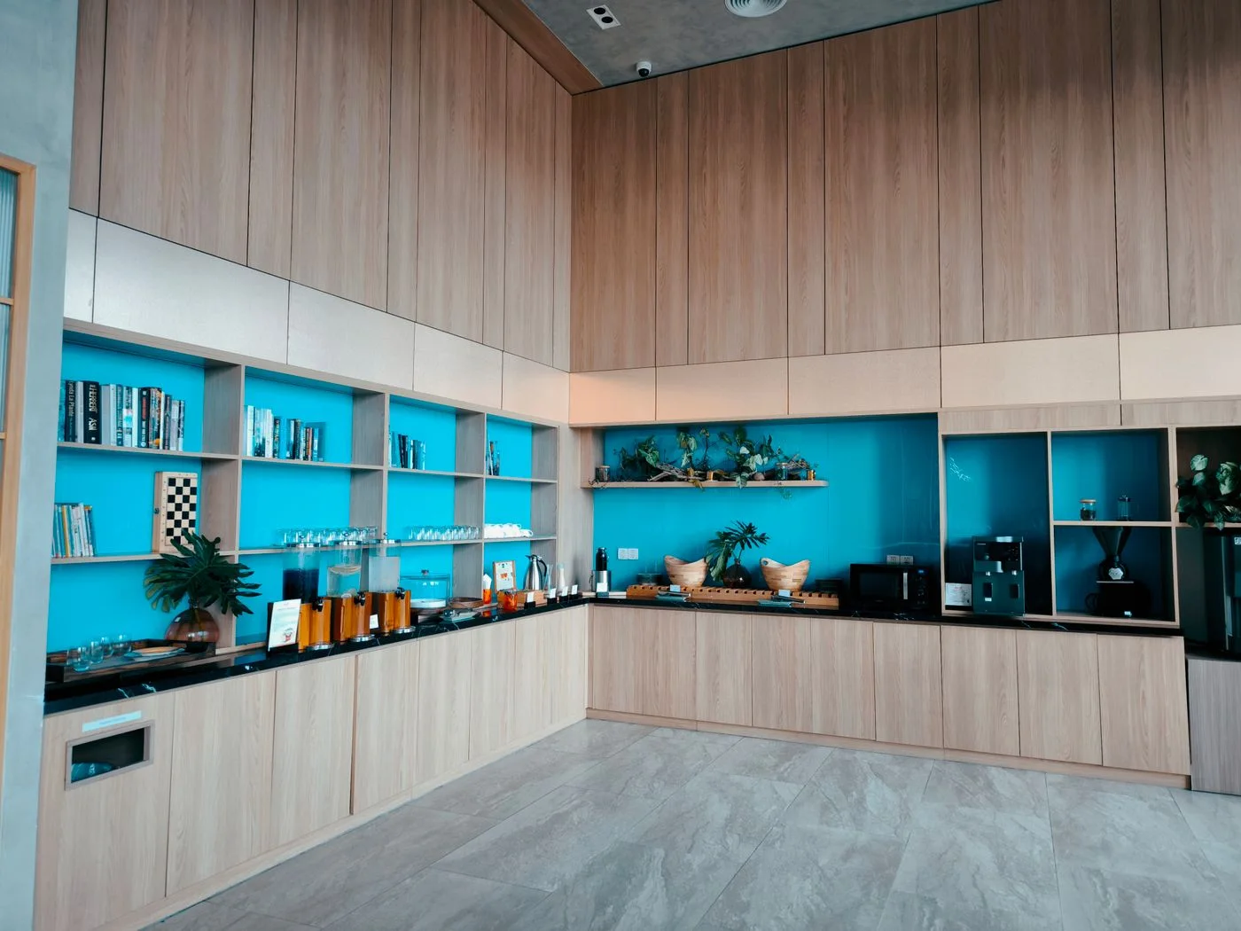 Bright and stylish office break room with refreshments and wooden shelving.
