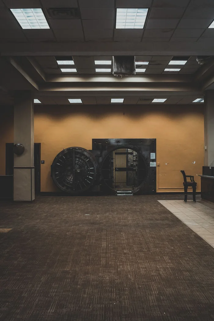 A spacious bank interior showcasing a large, open vault door under a modern ceiling.