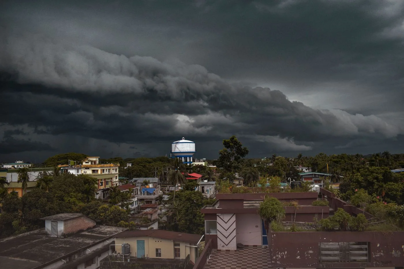 Aerial view of a small town with a water tower under dramatic storm clouds.