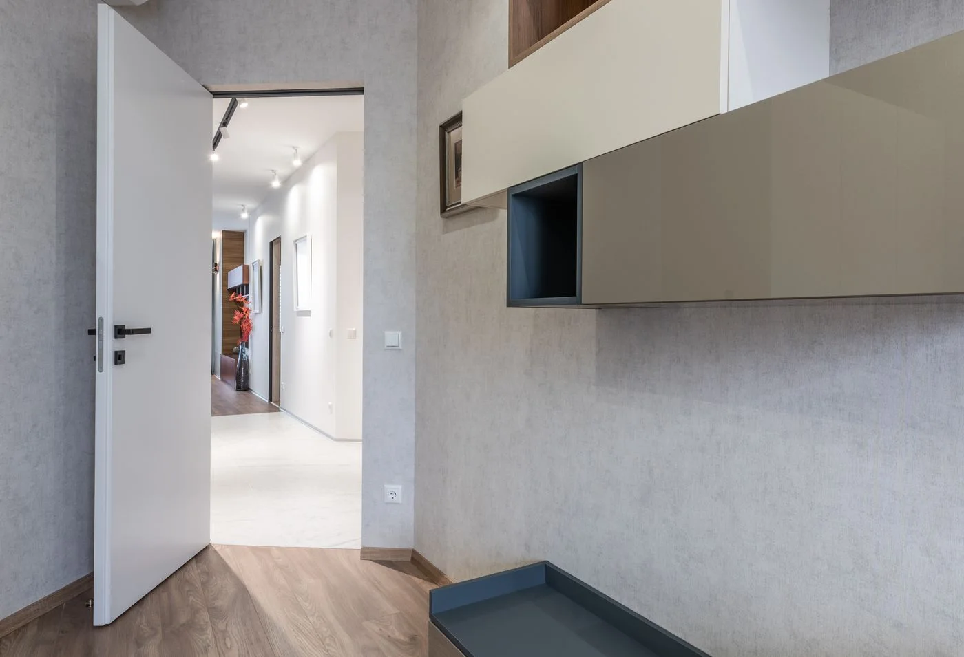 Interior design of contemporary new apartment room with empty shelves and opened door leading to light corridor.