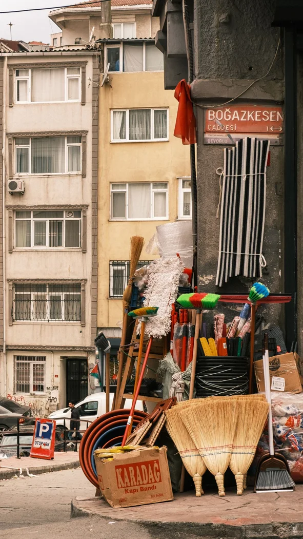 A quaint street corner shop displays an array of colorful cleaning supplies against an urban backdrop.