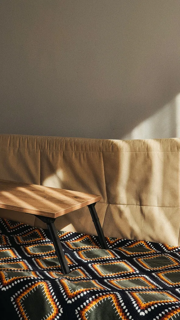 Sunlit cozy living room featuring a stylish geometric blanket over a beige sofa.