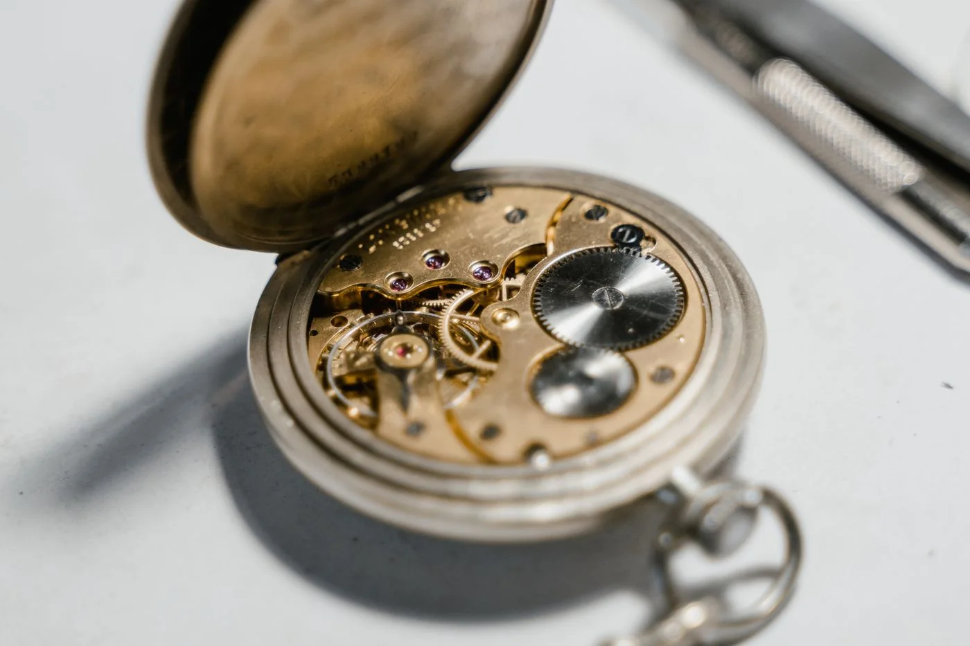 Detailed view of an open vintage pocket watch showcasing its intricate internal mechanism and gears.