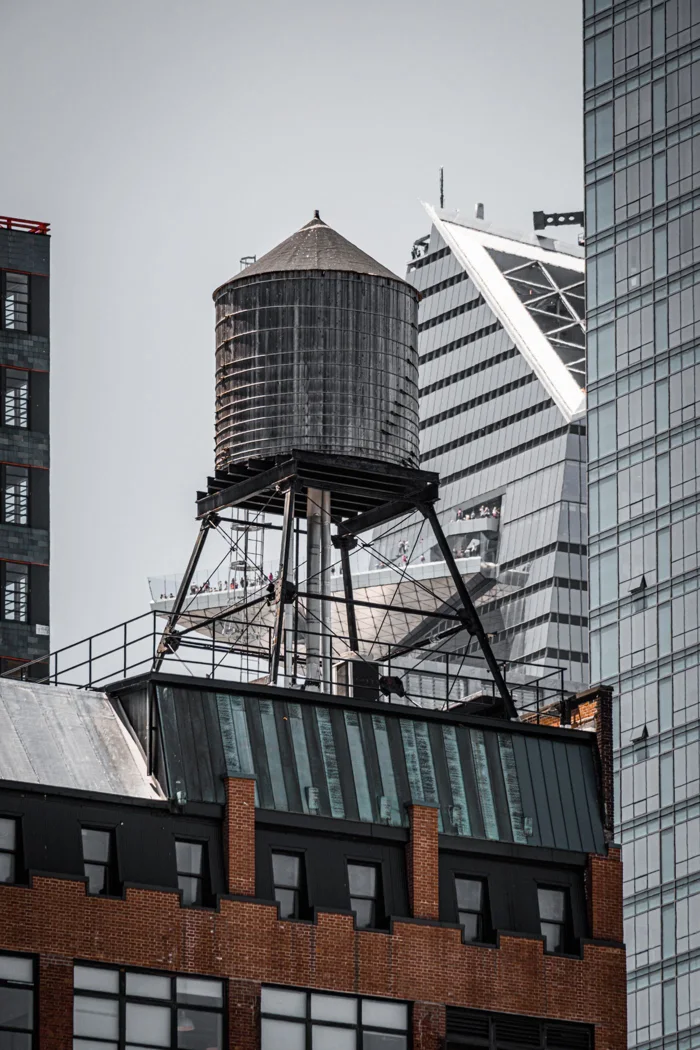 Classic New York rooftop view featuring a water tank against the modern skyline.