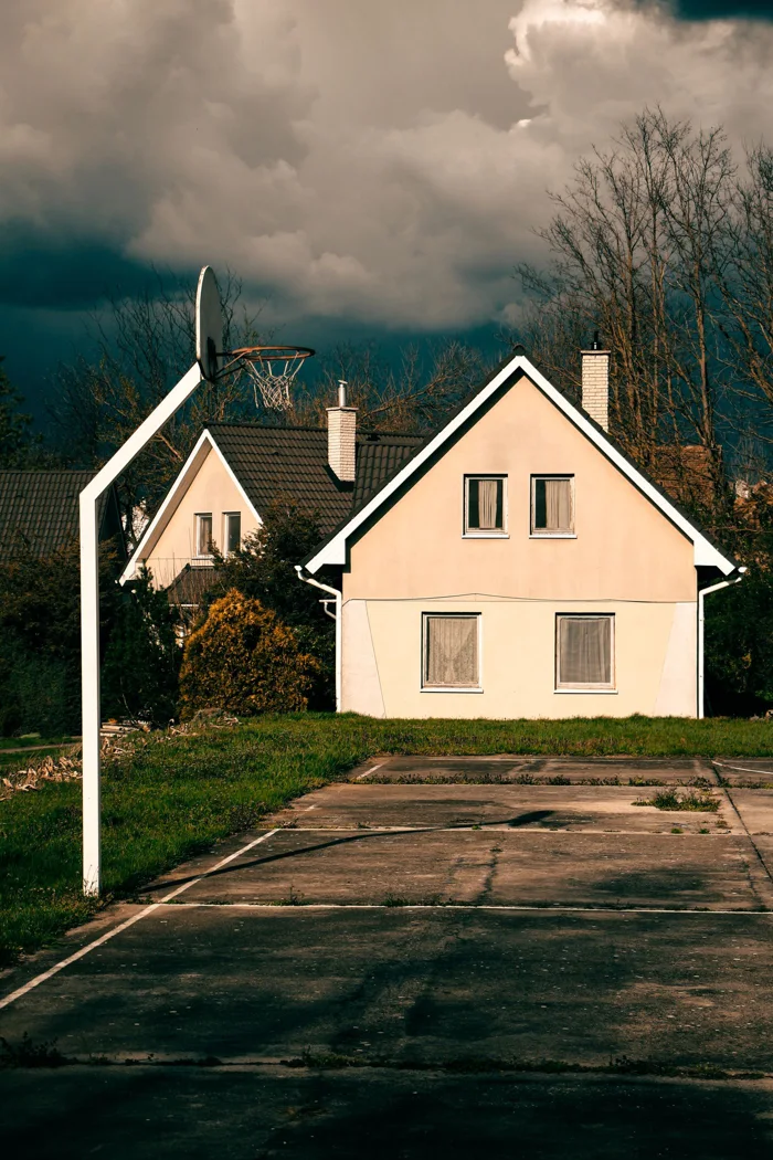 A deserted basketball court with houses in Pécel, Hungary, under dramatic skies.