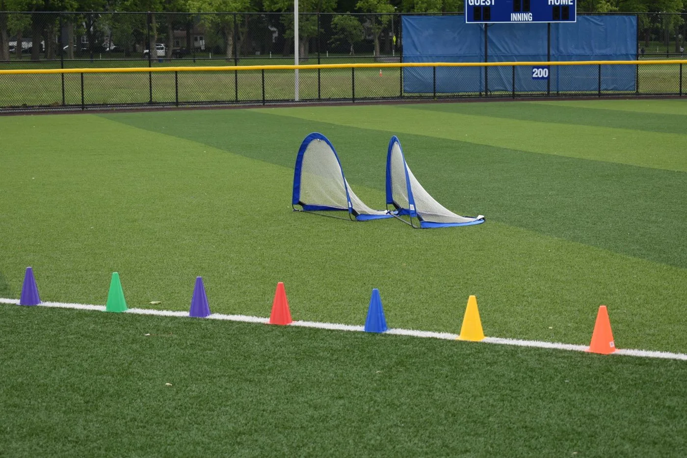 Colorful training cones and soccer nets on an empty sports field.