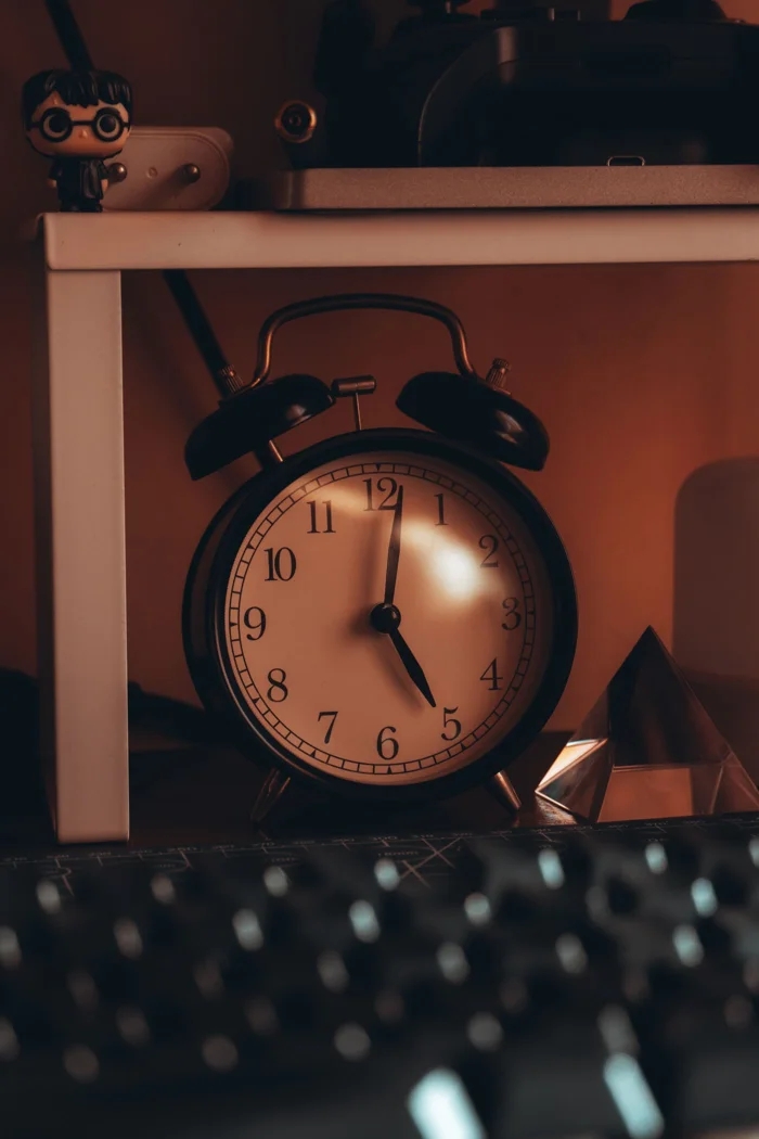 An antique alarm clock on a cozy bedside table casting artistic shadows with warm lighting.
