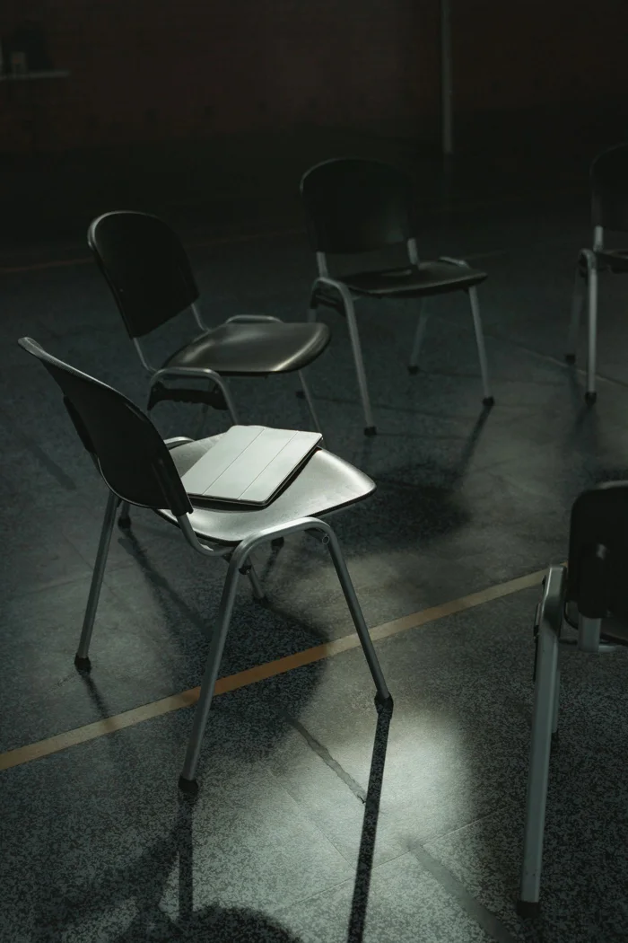 A dimly lit room with empty chairs arranged in a circle, suggesting a group meeting or discussion.