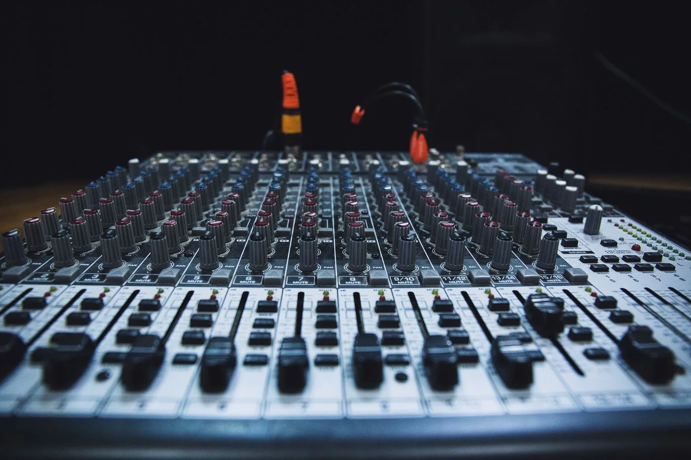 Close-up of audio mixing console with faders and knobs in studio lighting.