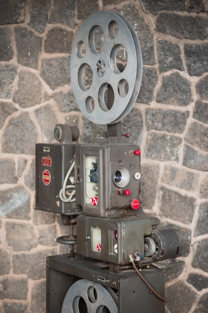 Classic vintage film projector displayed against a rustic stone wall.