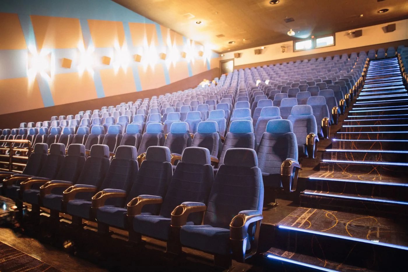 Spacious cinema hall with empty rows of blue chairs, ready for moviegoers.